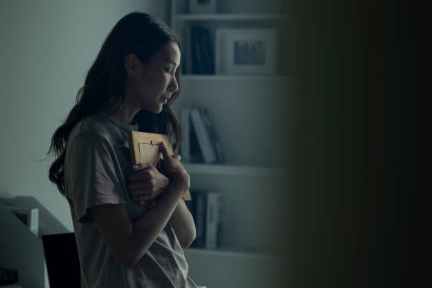 Person holding framed photo, thoughtful indoors.